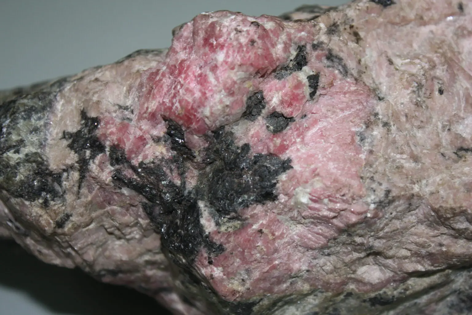 Figura 3a. Rodocrosita (color rosa) y óxidos de manganeso (colores oscuros), Yacimiento epitermal de sulfuración intermedia.
